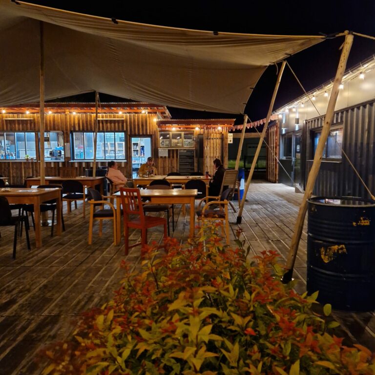 Bar guinguette en container au Trente-Trois à Pratz, avec terrasse en bois et éclairage nocturne.