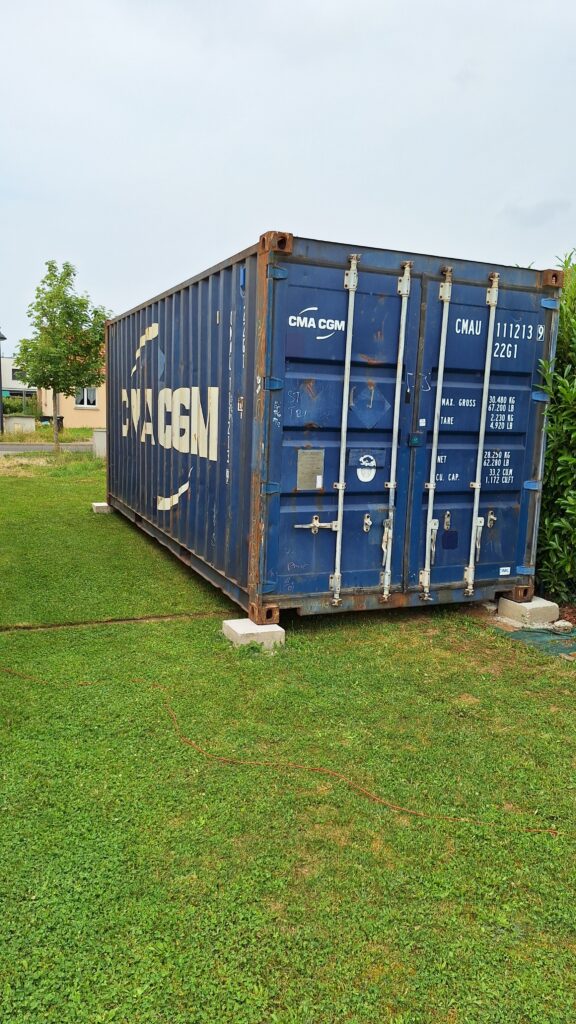 Container maritime de 20 pieds installé dans un jardin à Aulnois-sur-Seille pour le stockage de matériel de jardin.