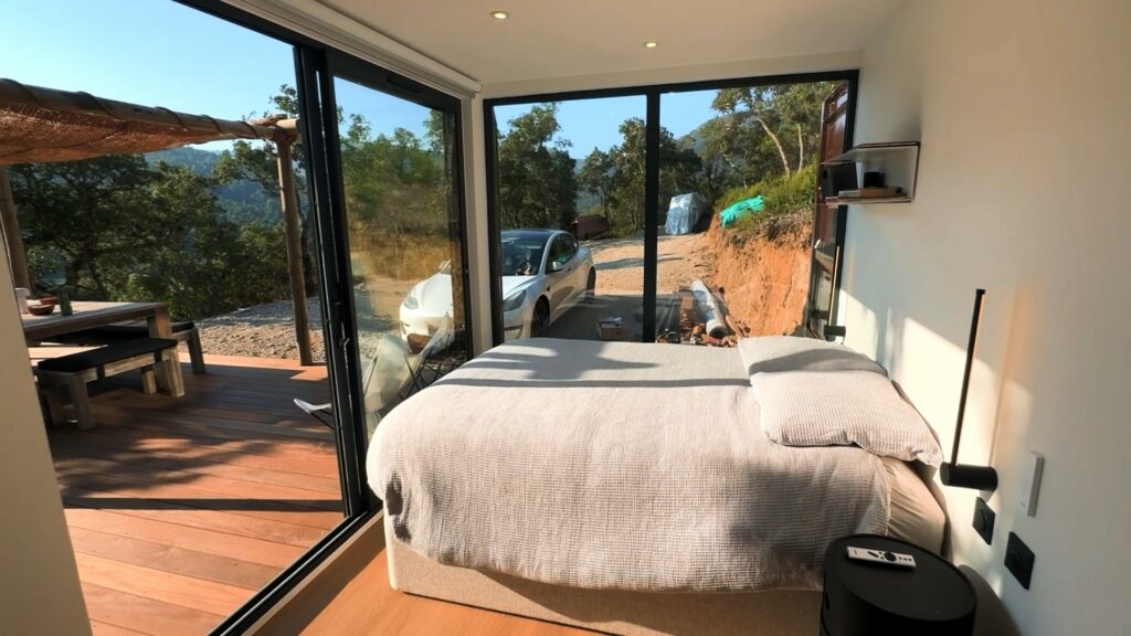 Intérieur lumineux d'un gîte en container 20 pieds avec vue sur une terrasse en bois et l'extérieur naturel à La Môle.