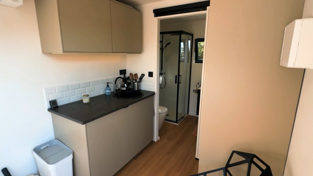 Aménagement intérieur d'un gîte en container 20 pieds, avec kitchenette et salle de bain moderne.