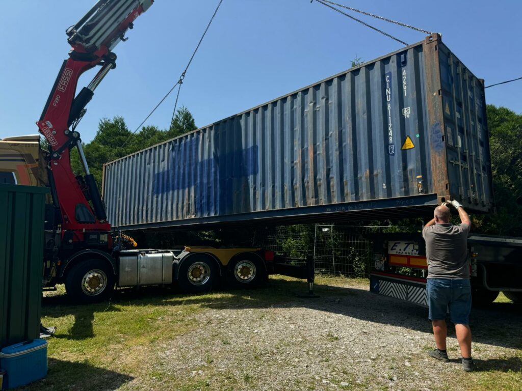 Un container maritime de 40 pieds soulevé et positionné par une grue à la Brasserie La Chillossa pour une solution de stockage.