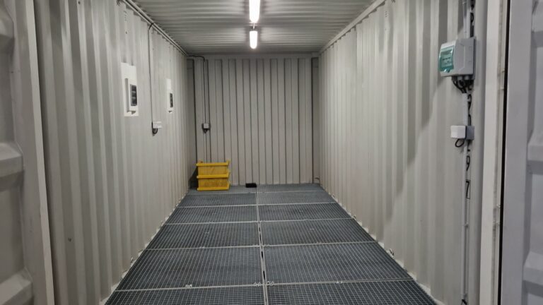 Intérieur d'un container aménagé de 20 pieds avec un plancher en caillebotis, éclairage LED et installations électriques.